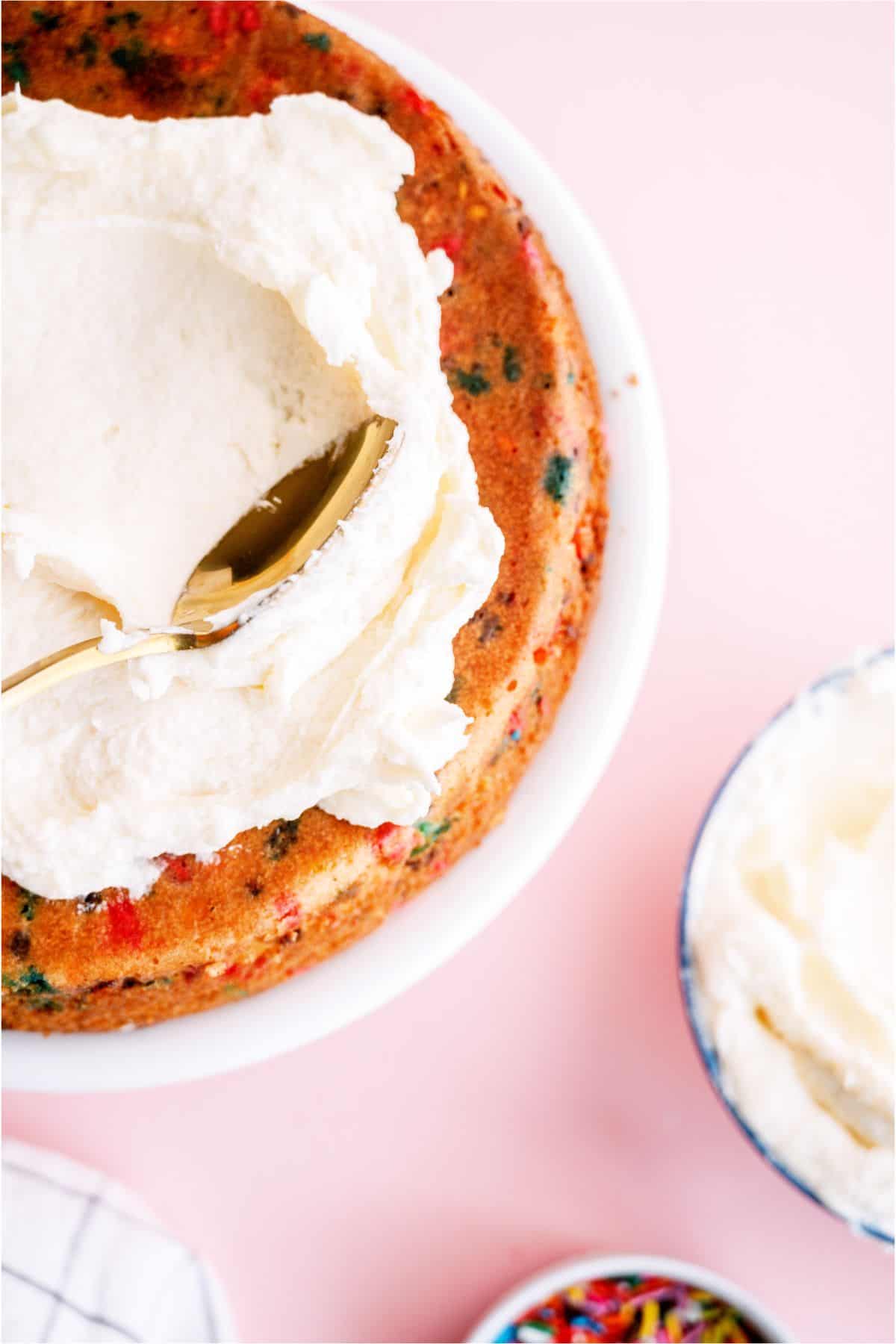 Spreading frosting on top of Homemade Funfetti Cake