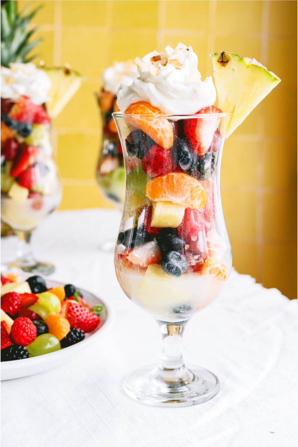 Pina Colada Fruit Salad in a glass topped with whip cream and garnished with a pineapple