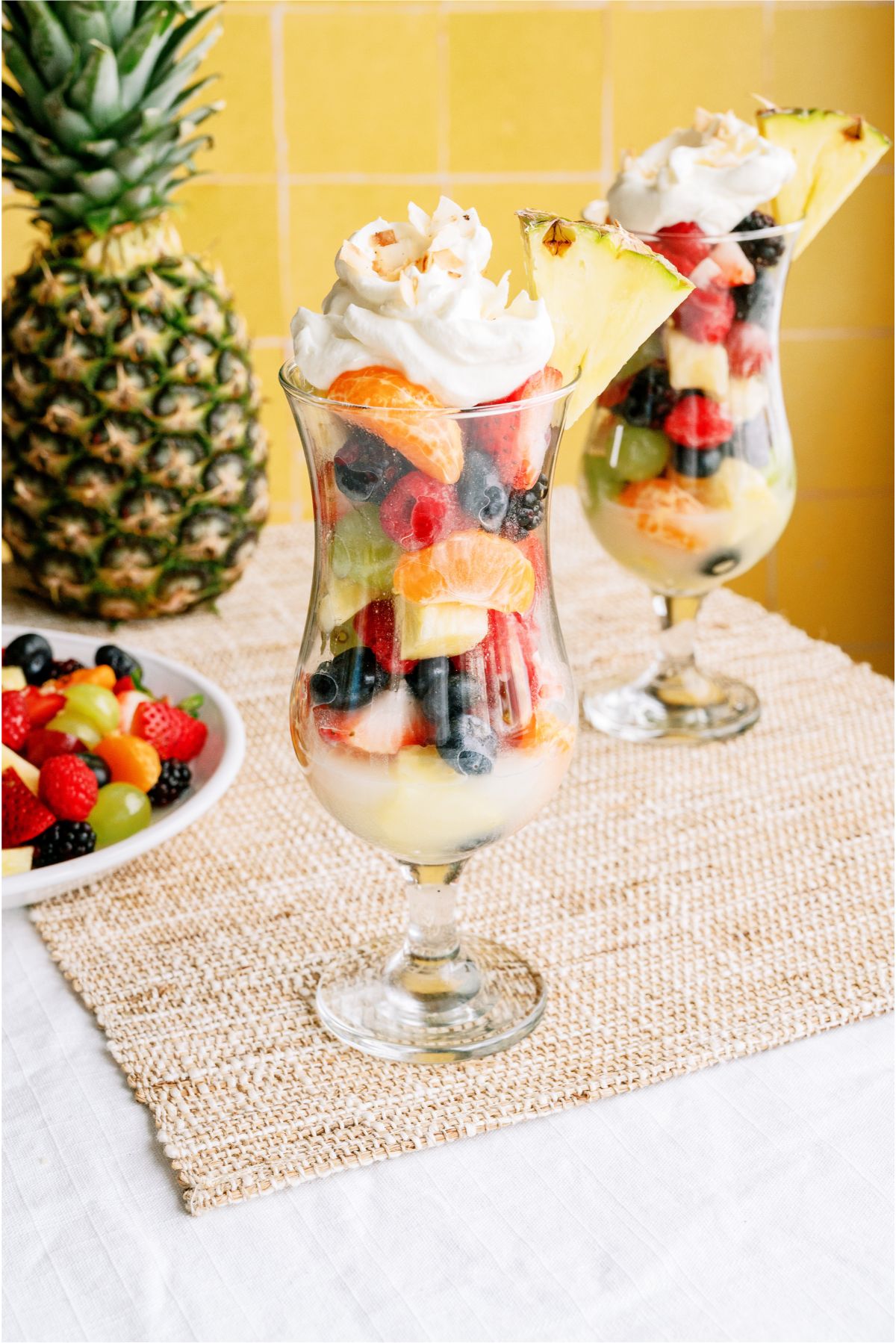 A glass filled with Pina Colada Fruit Salad topped with whip cream and garnished with pineapple