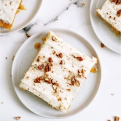 Slices of Sheet Pan Carrot Cake and Cream Cheese Frosting on white plates.