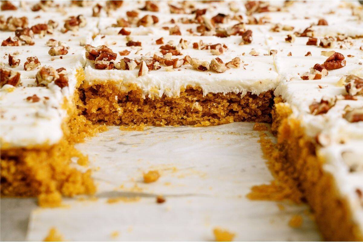 Sheet Pan Carrot Cake and Cream Cheese Frosting in sheet pan with pieces missing.