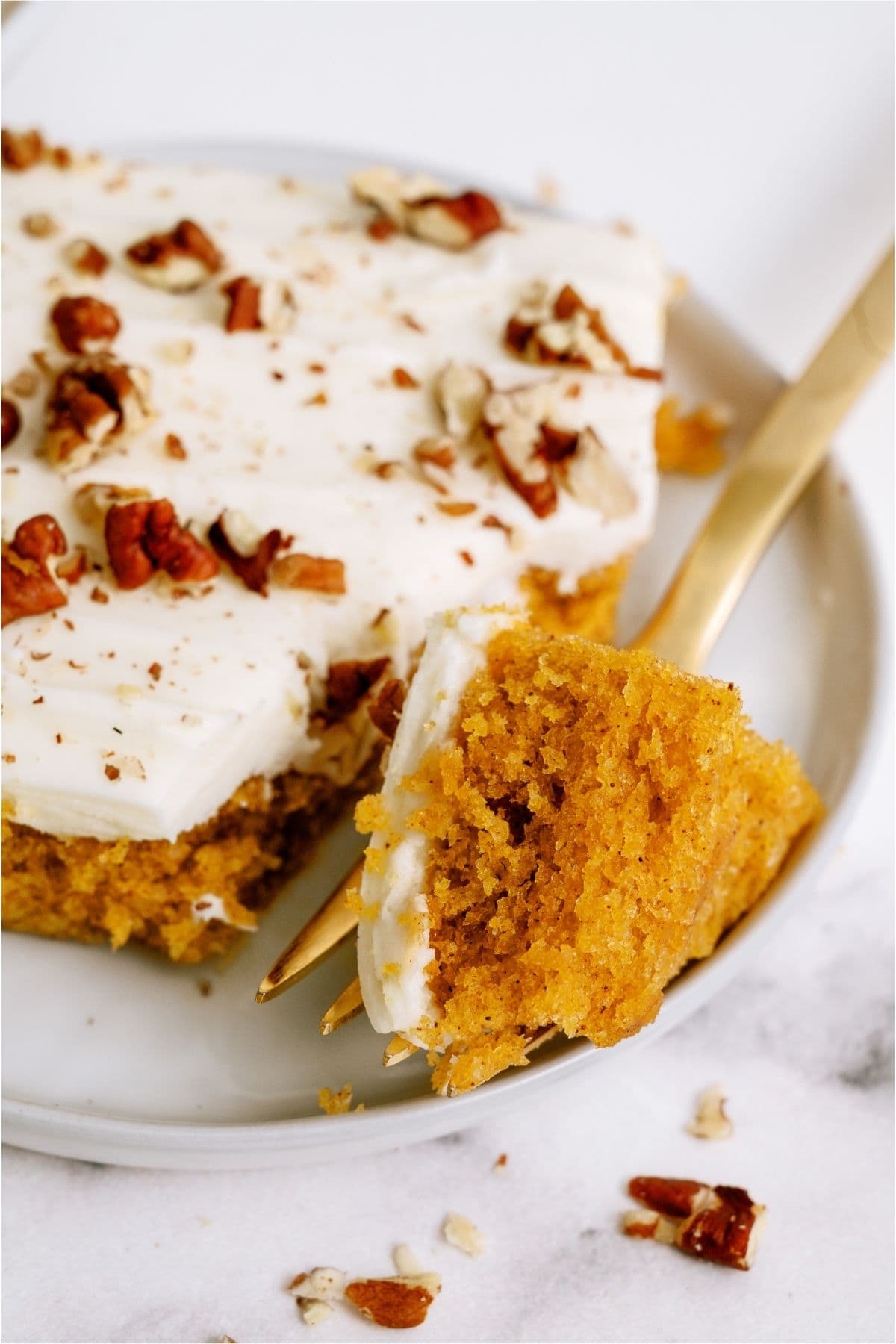 A fork taking a bite out of a square of Sheet Pan Carrot Cake and Cream Cheese Frosting.