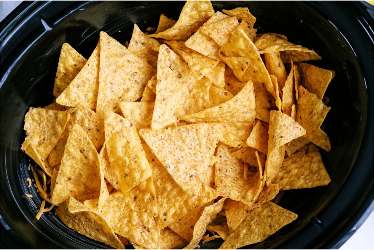 A layer of tortilla chips in the bottom of a slow cooker