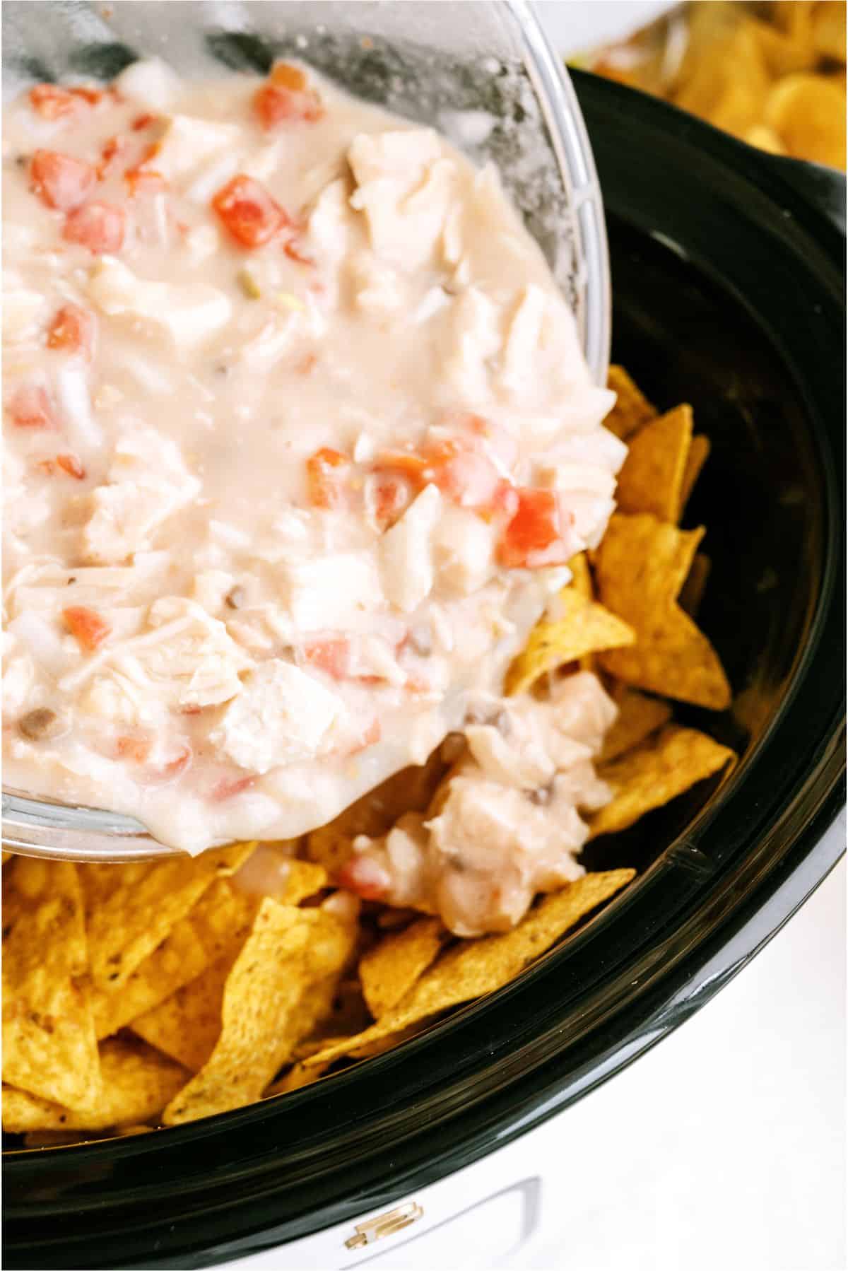 Pouring half of chicken mixture on top of tortilla chips