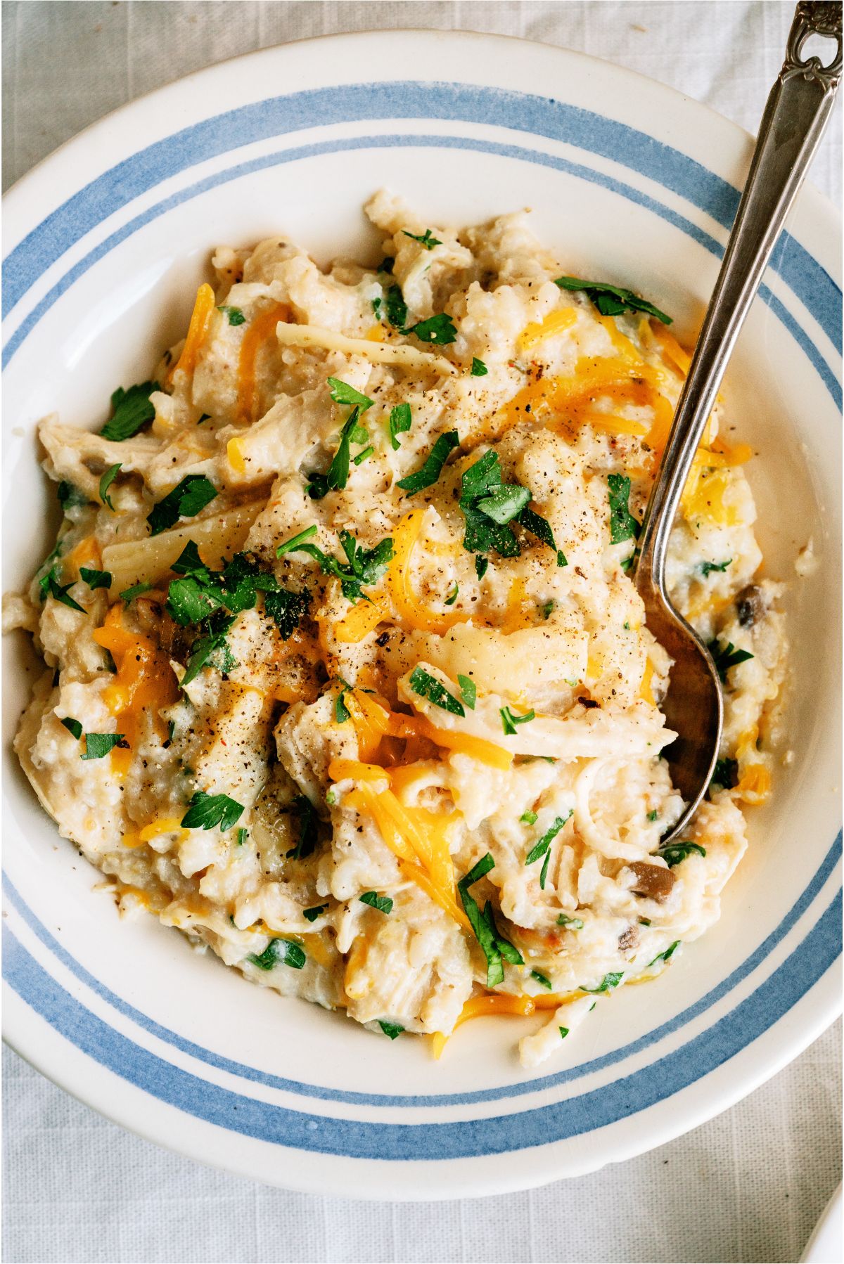 A serving of Slow Cooker Parmesan Chicken And Rice on a plate with a spoon