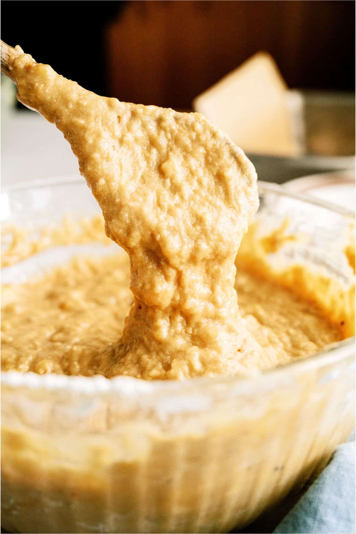 Dry ingredients mixed into banana mixture in mixing bowl with wooden spoon