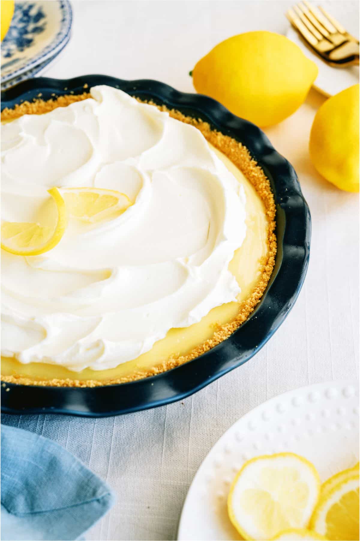 Creamy Lemon Pie in pie dish with fresh lemons on the side