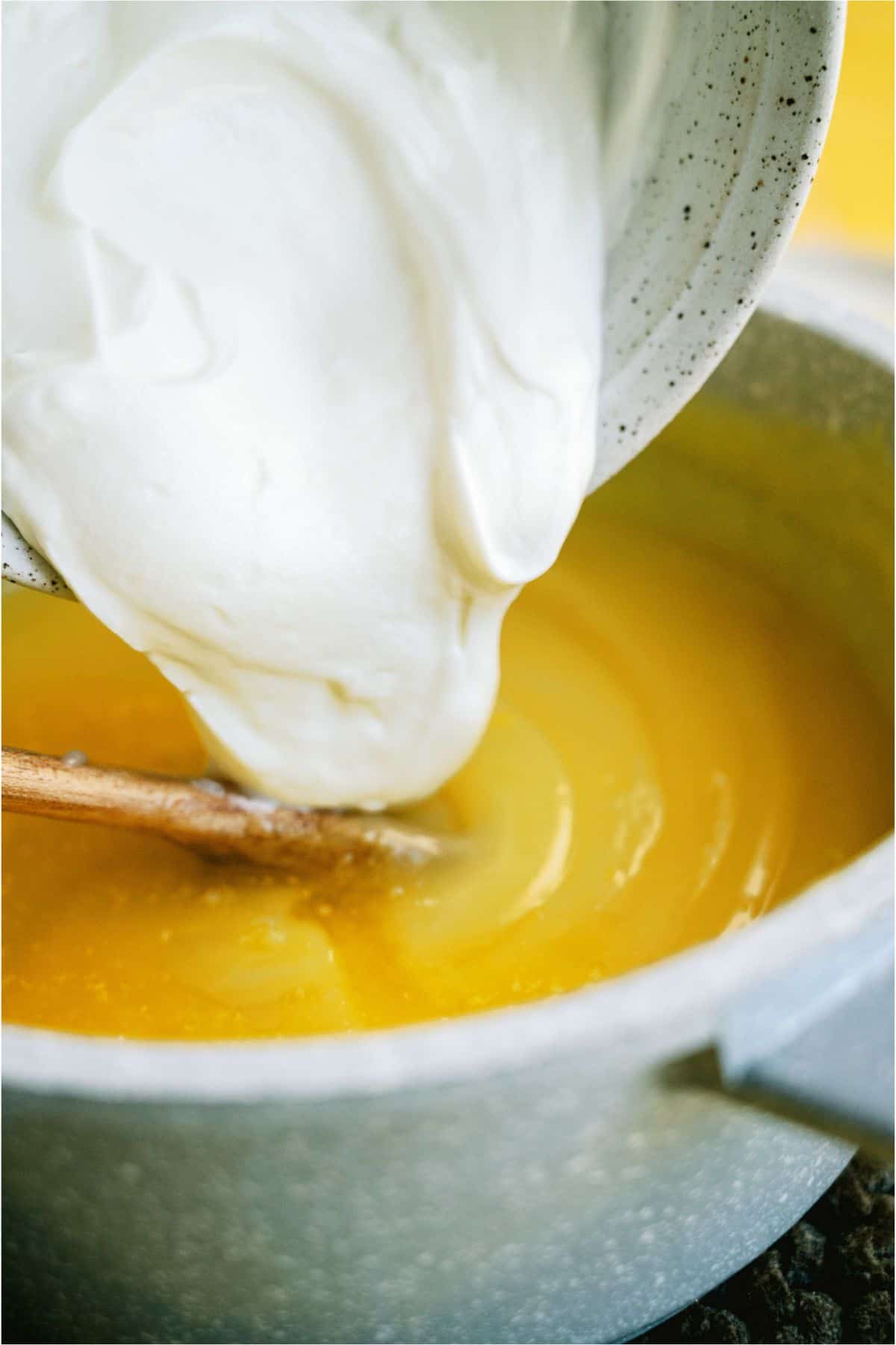 Adding greek yogurt mixture to lemon mixture in saucepan