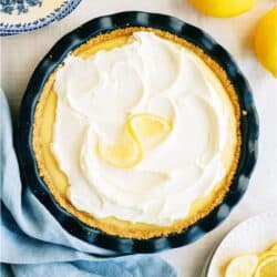 Top view of creamy lemon pie with fresh lemons in the background.