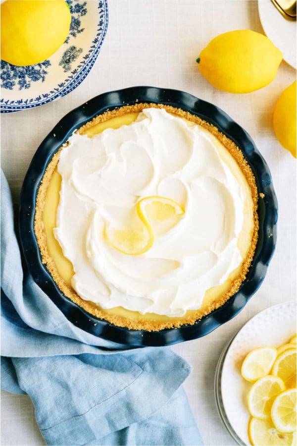 Top view of creamy lemon pie with fresh lemons in the background.