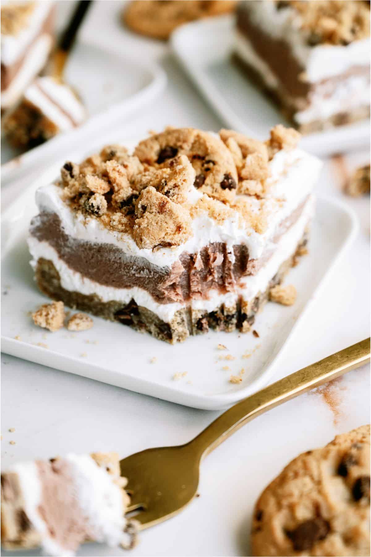 A slice of Layered Chocolate Chip Cookie Dessert on a plate with a fork