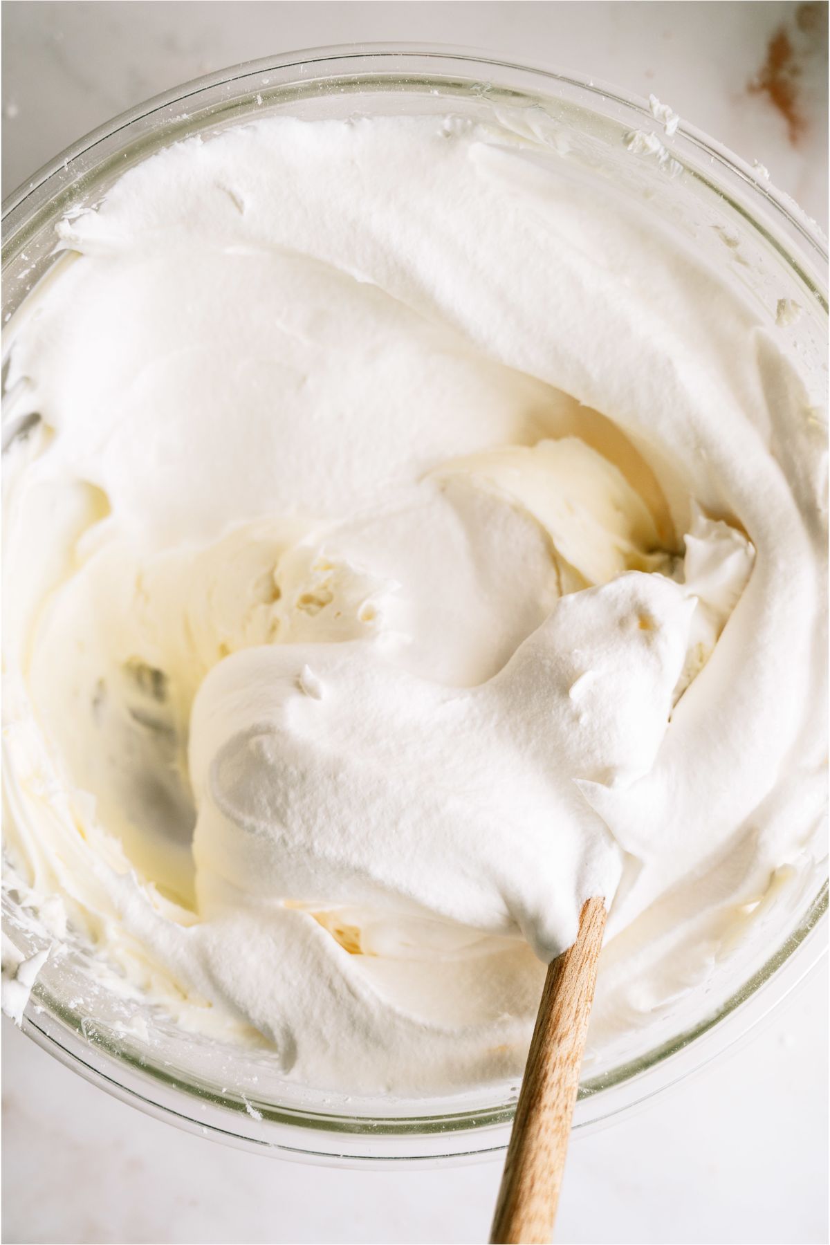 Adding cool whip to the cream cheese mixture in a mixing bowl