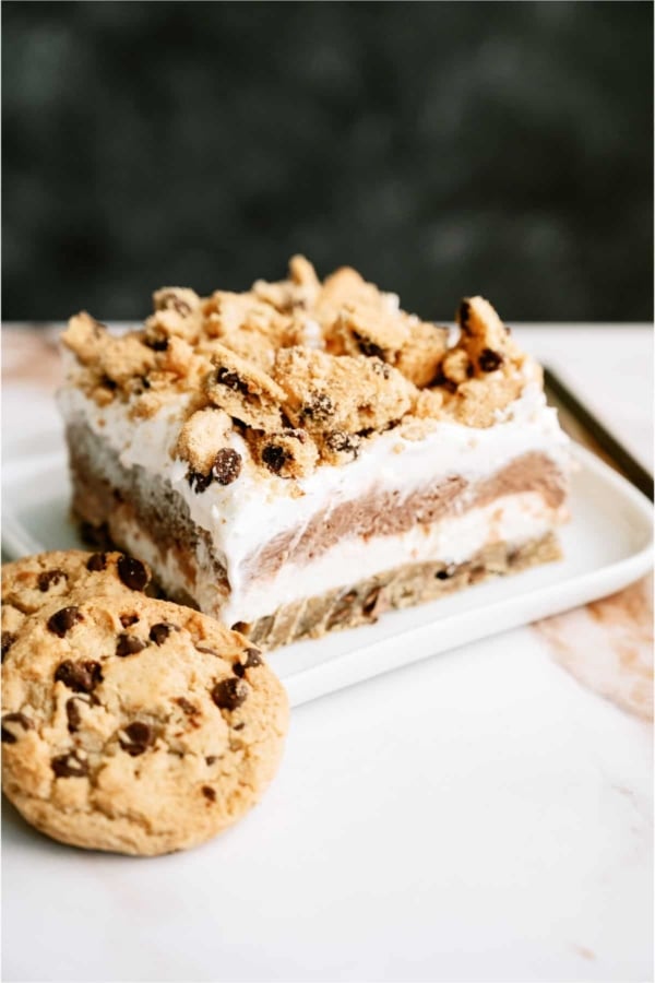 A slice of Layered Chocolate Chip Cookie Dessert on a plate with a cookie.