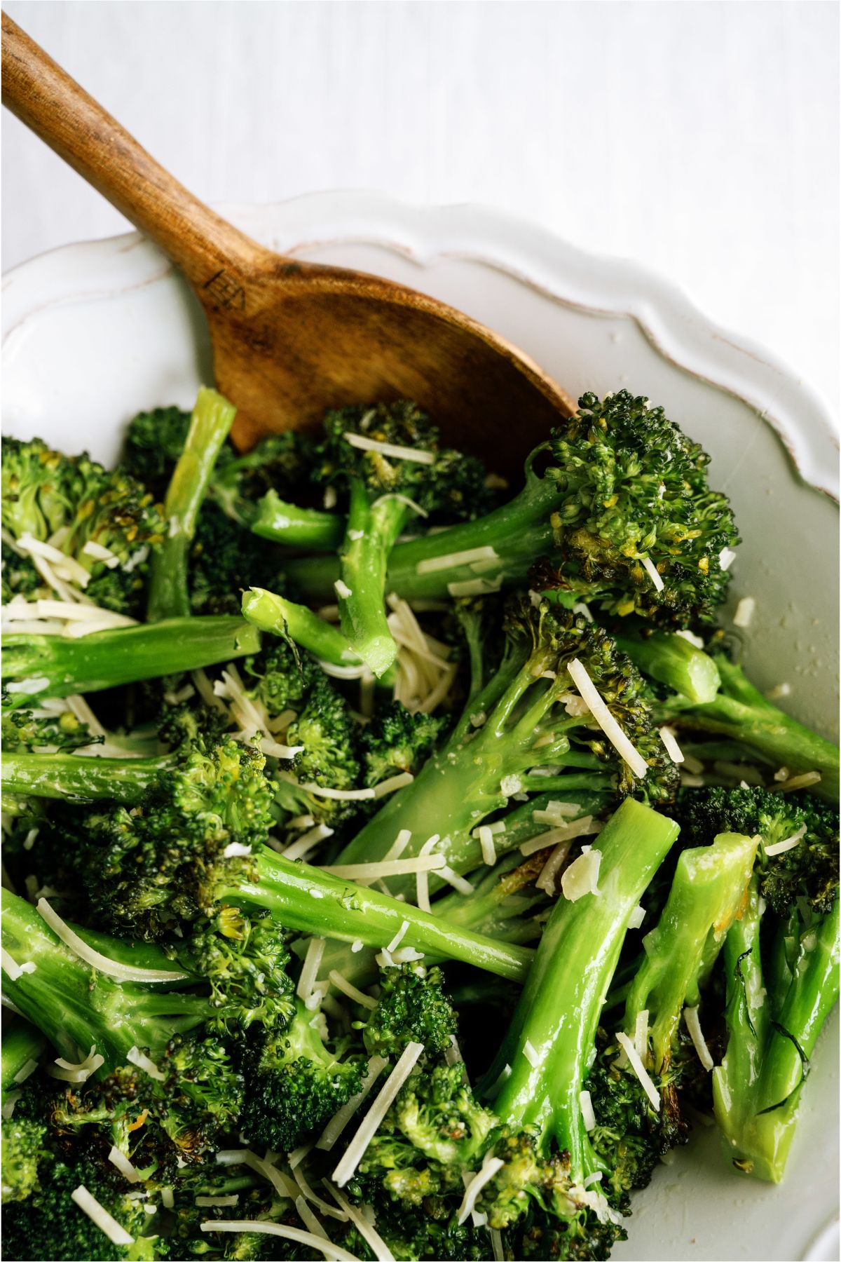 A bowl of Oven Roasted Parmesan Broccoli with a wooden spoon
