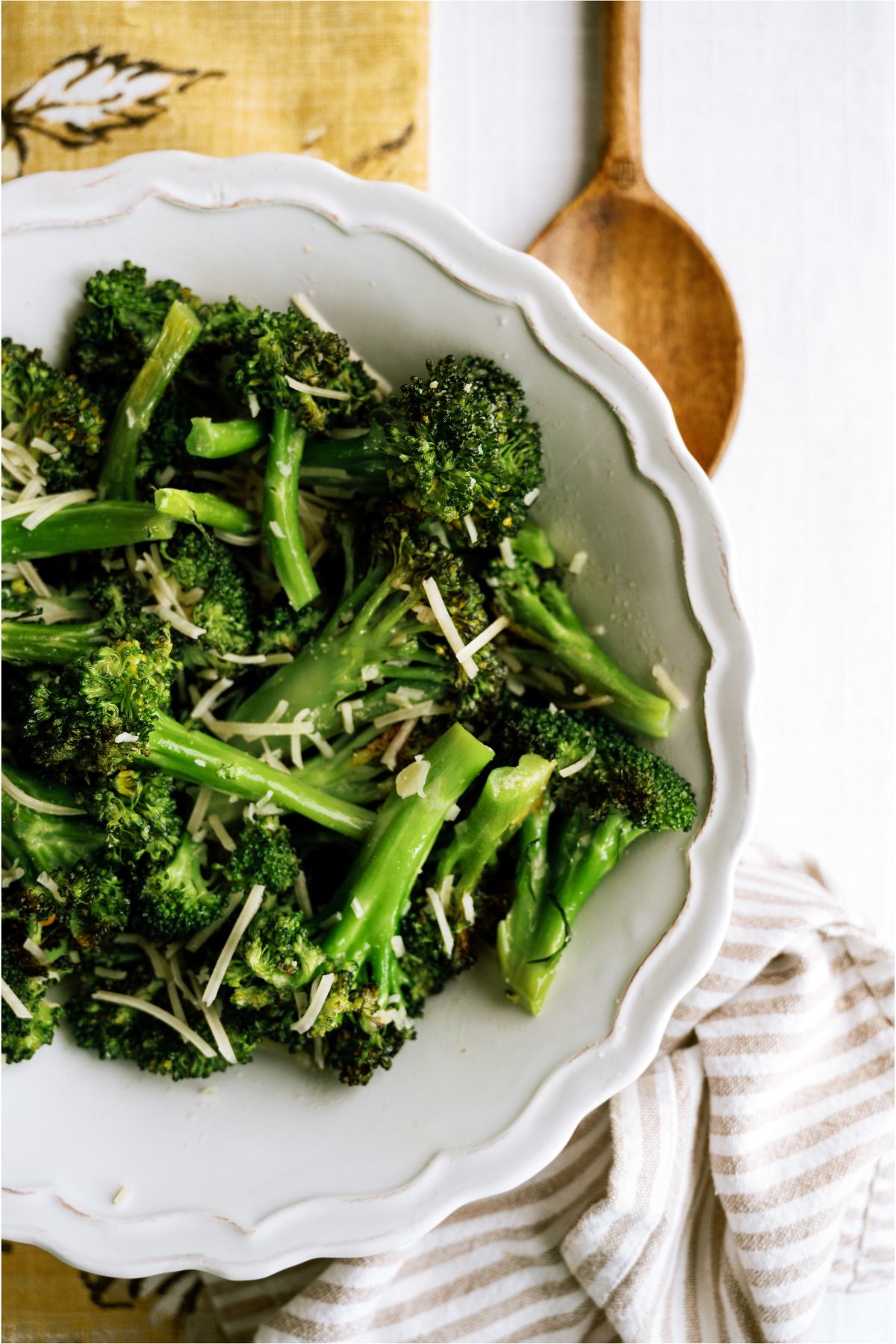 A bowl of Oven Roasted Parmesan Broccoli with a wooden spoon in the background