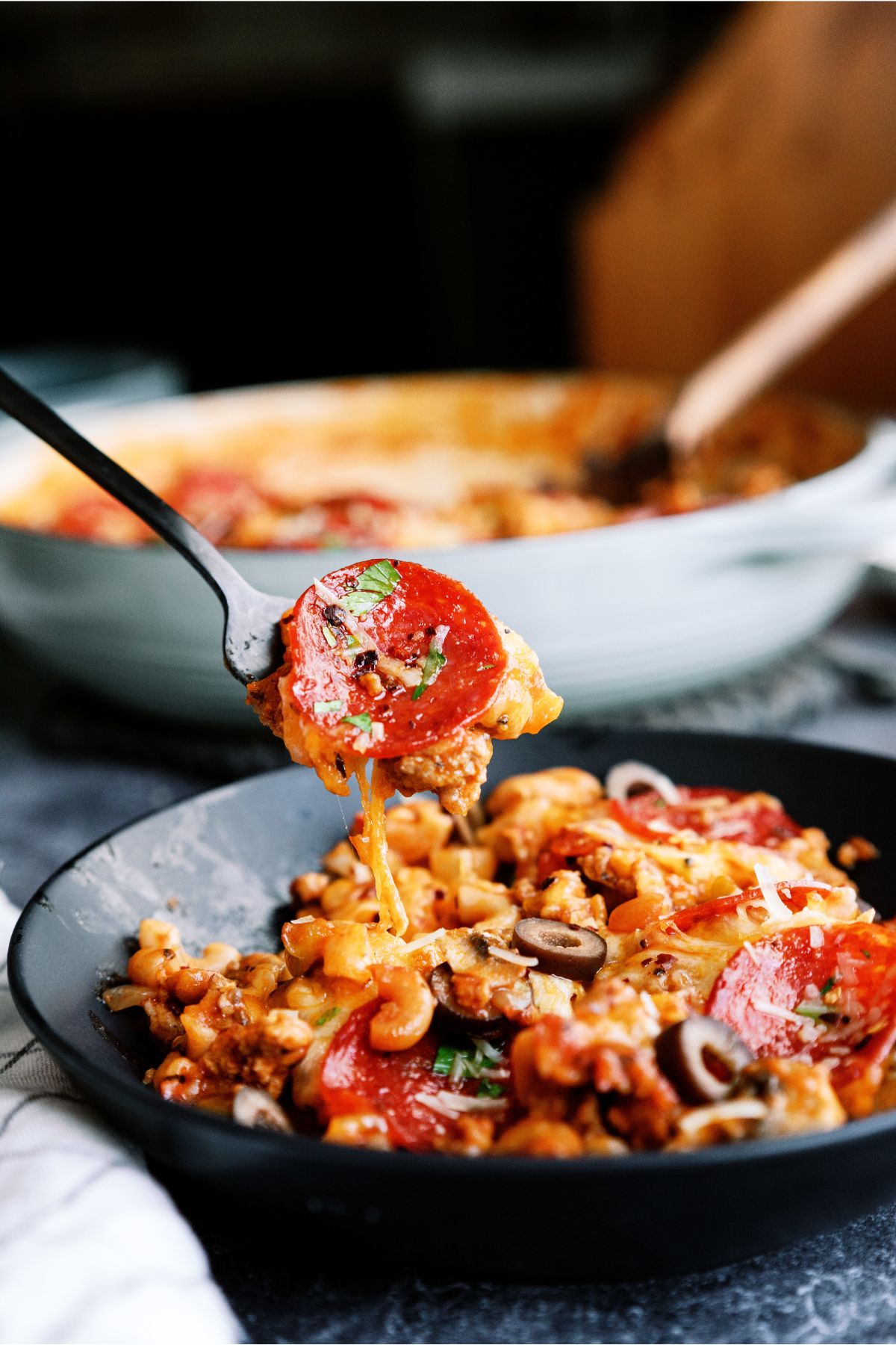 A serving of Pizza Skillet Pasta in a bowl with a fork lifting a bite out
