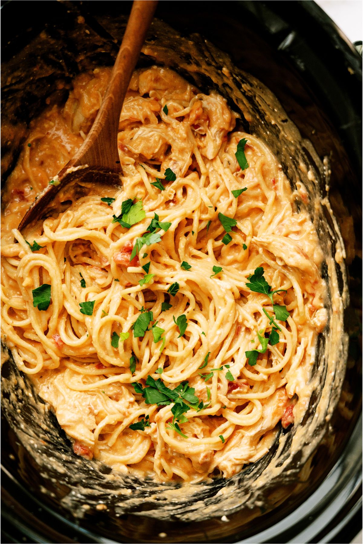 Slow Cooker Chicken Spaghetti in the slow cooker with a wooden spoon