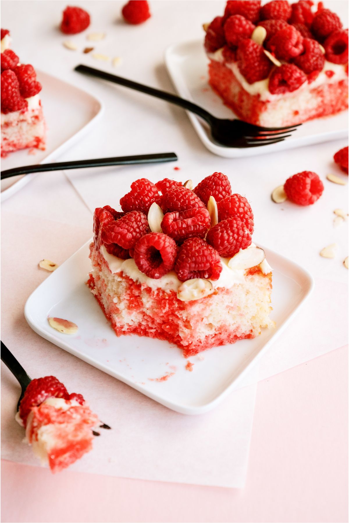 Slices of White Raspberry Poke Cake on plates with forks