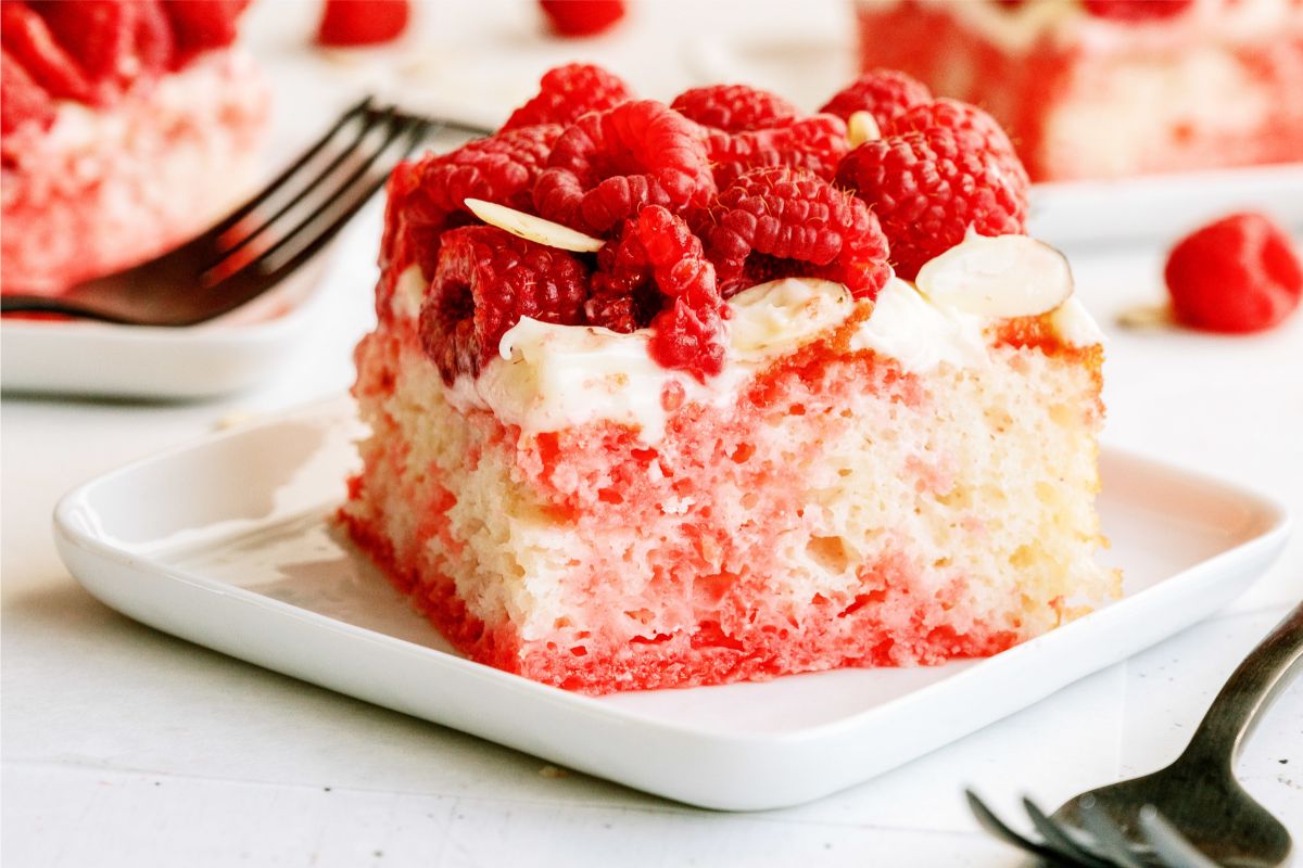 A slice of White Raspberry Poke Cake on a plate