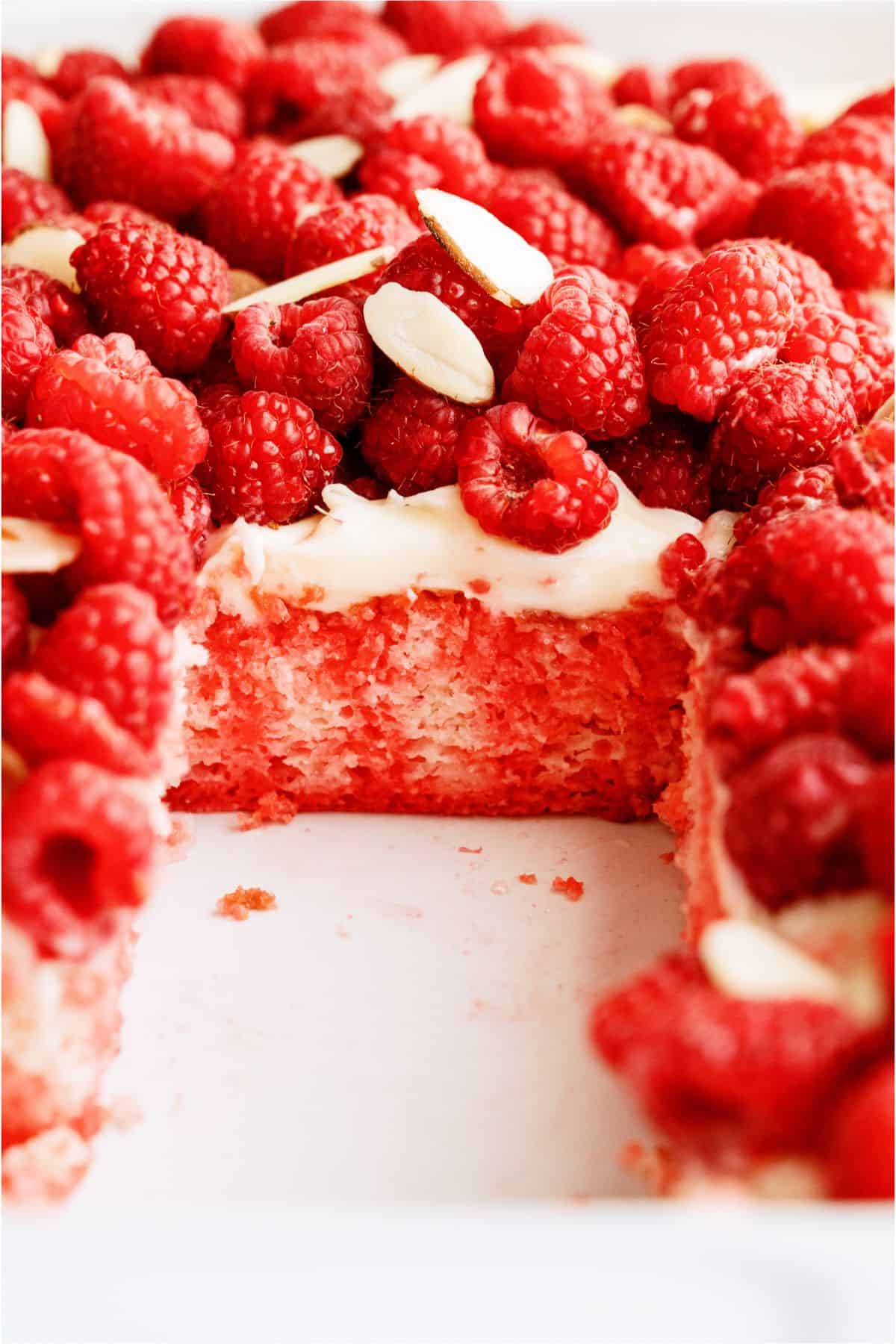 White Raspberry Poke Cake in cake dish with a slice missing