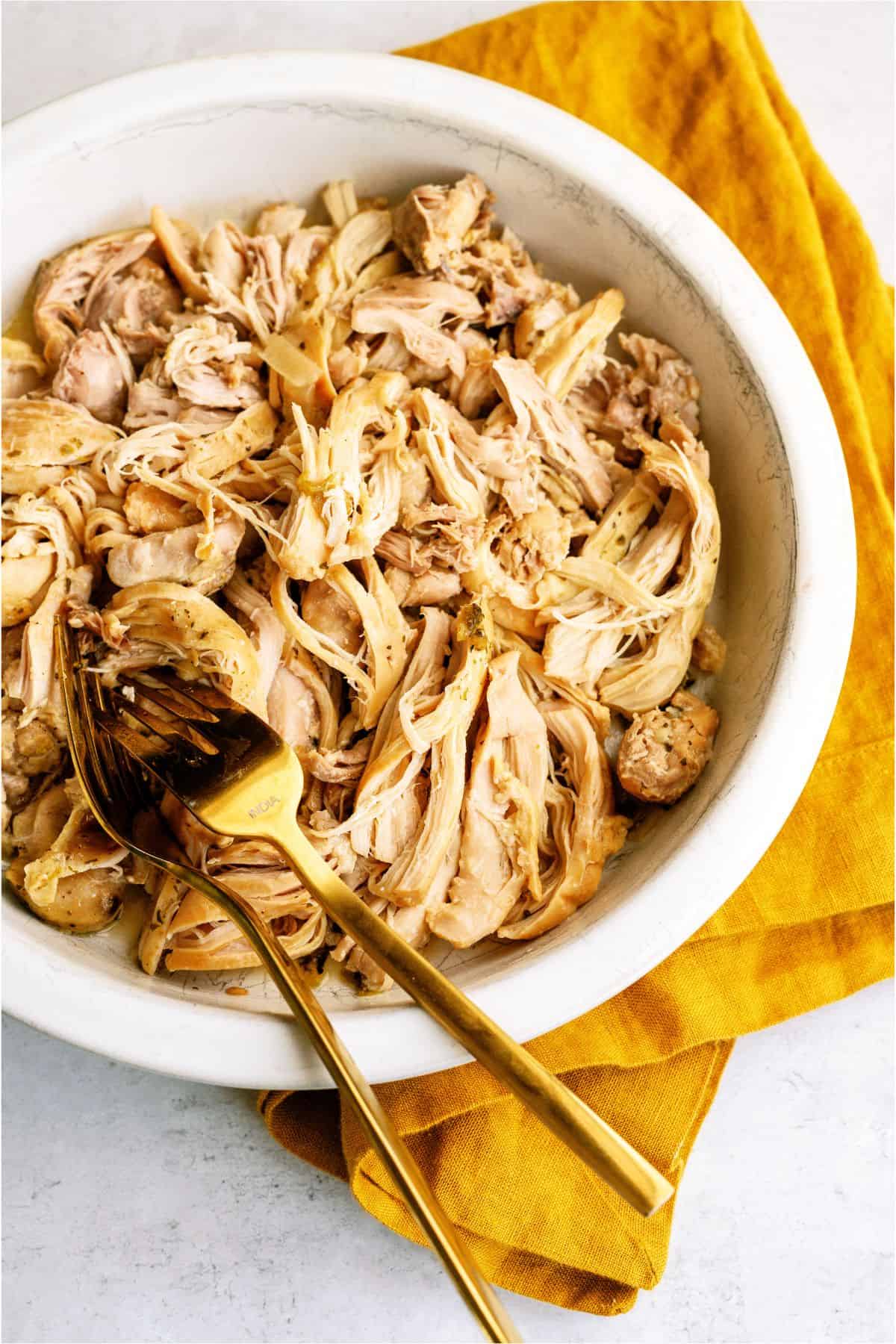 Shredded chicken in a bowl with 2 forks