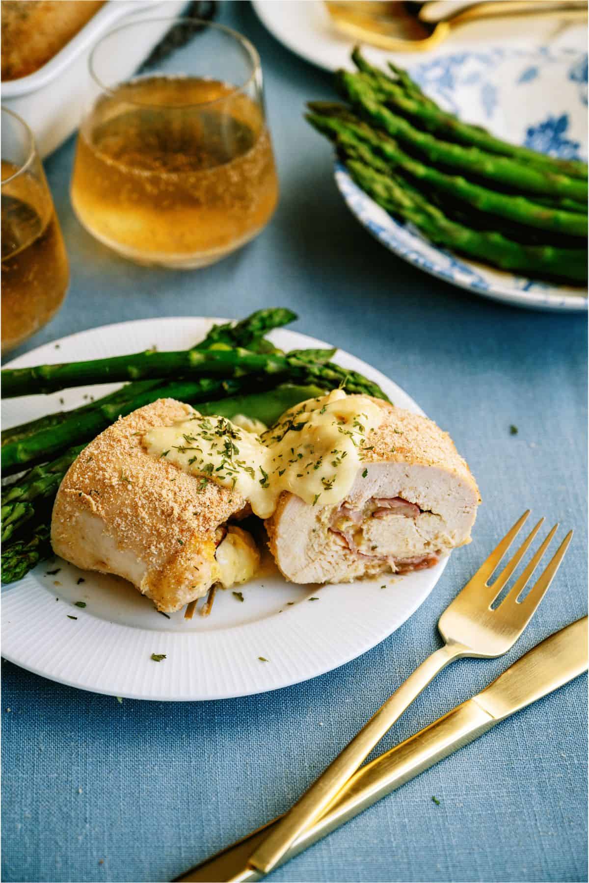 A plate of Asparagus with a Malibu Stuffed Chicken cut in half