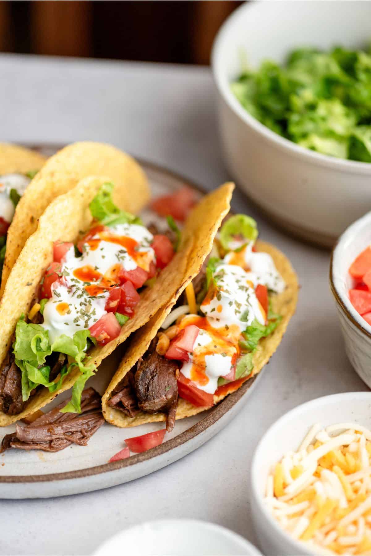 A plate of Slow Cooker Shredded Beef Tacos with toppings