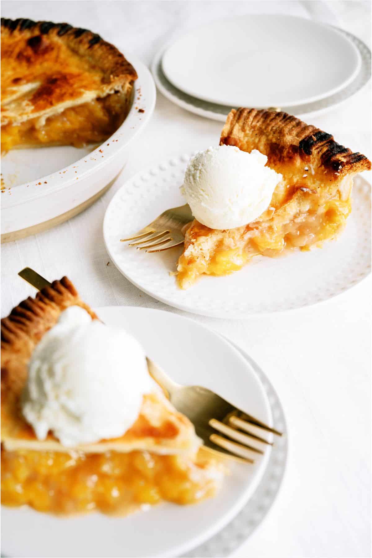 2 servings of Classic Peach Pie on small plates with forks. The remaining peach pie in the background.