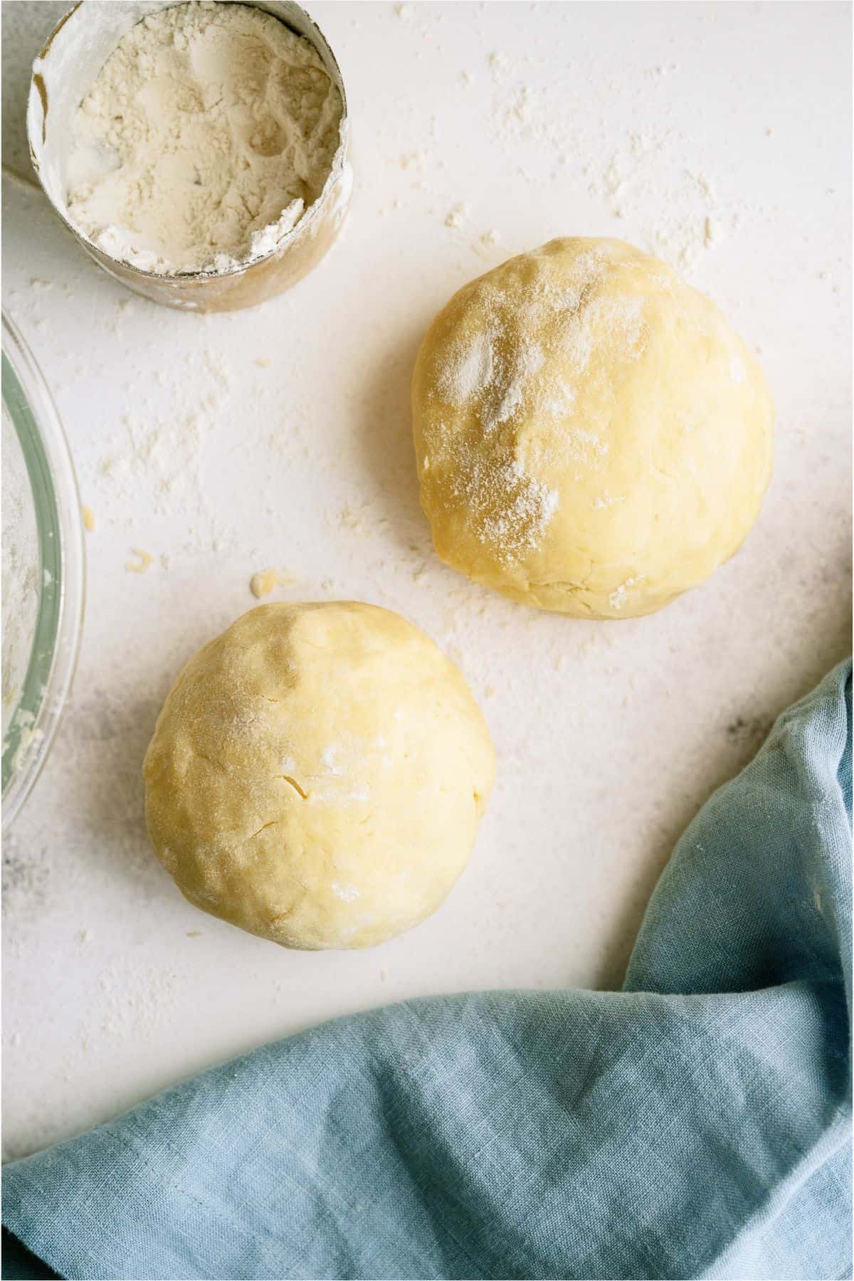 2 pie crust dough balls sitting on a countertop.