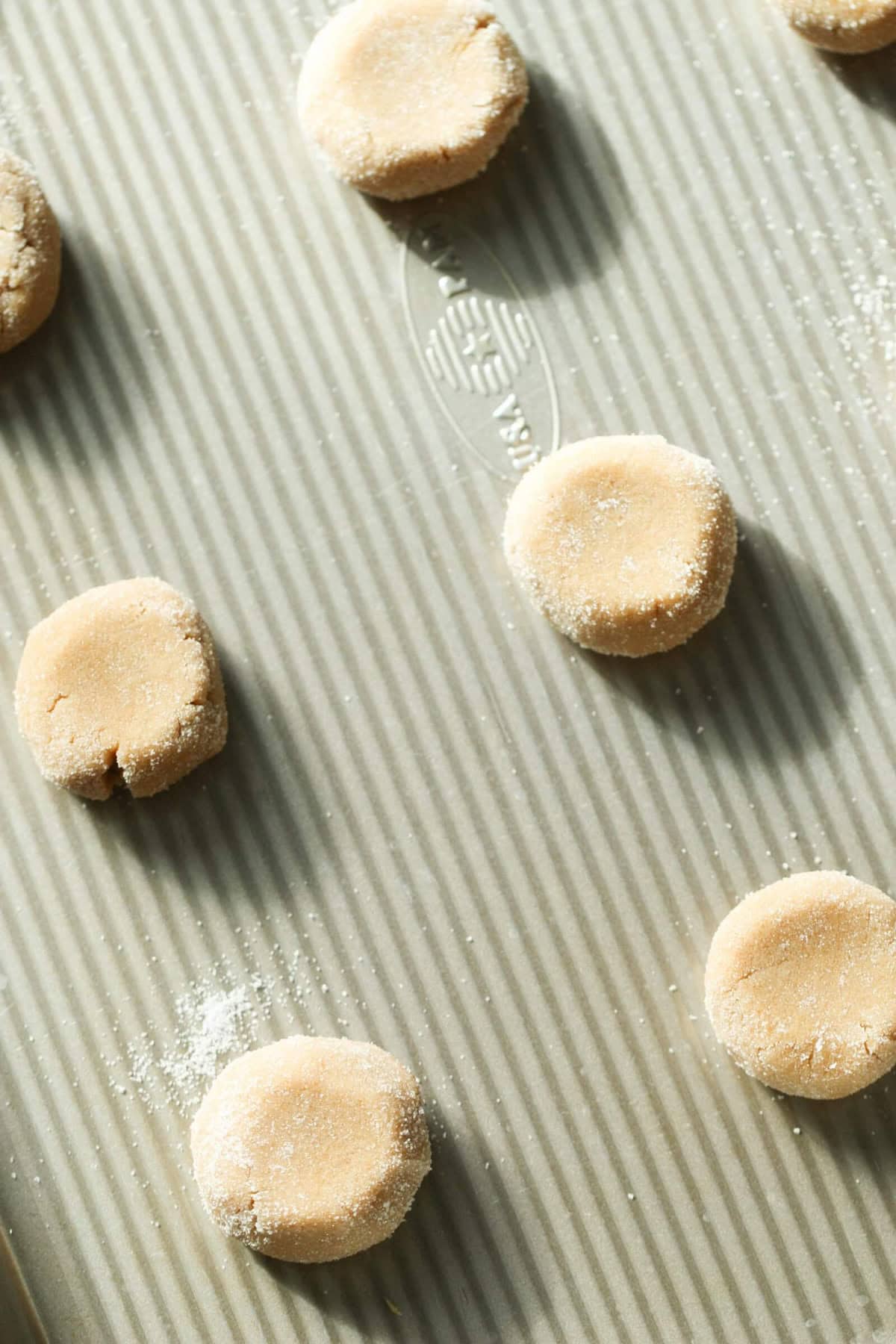 Unbaked cookie dough rounds are placed evenly on a grooved baking sheet, ready for baking.