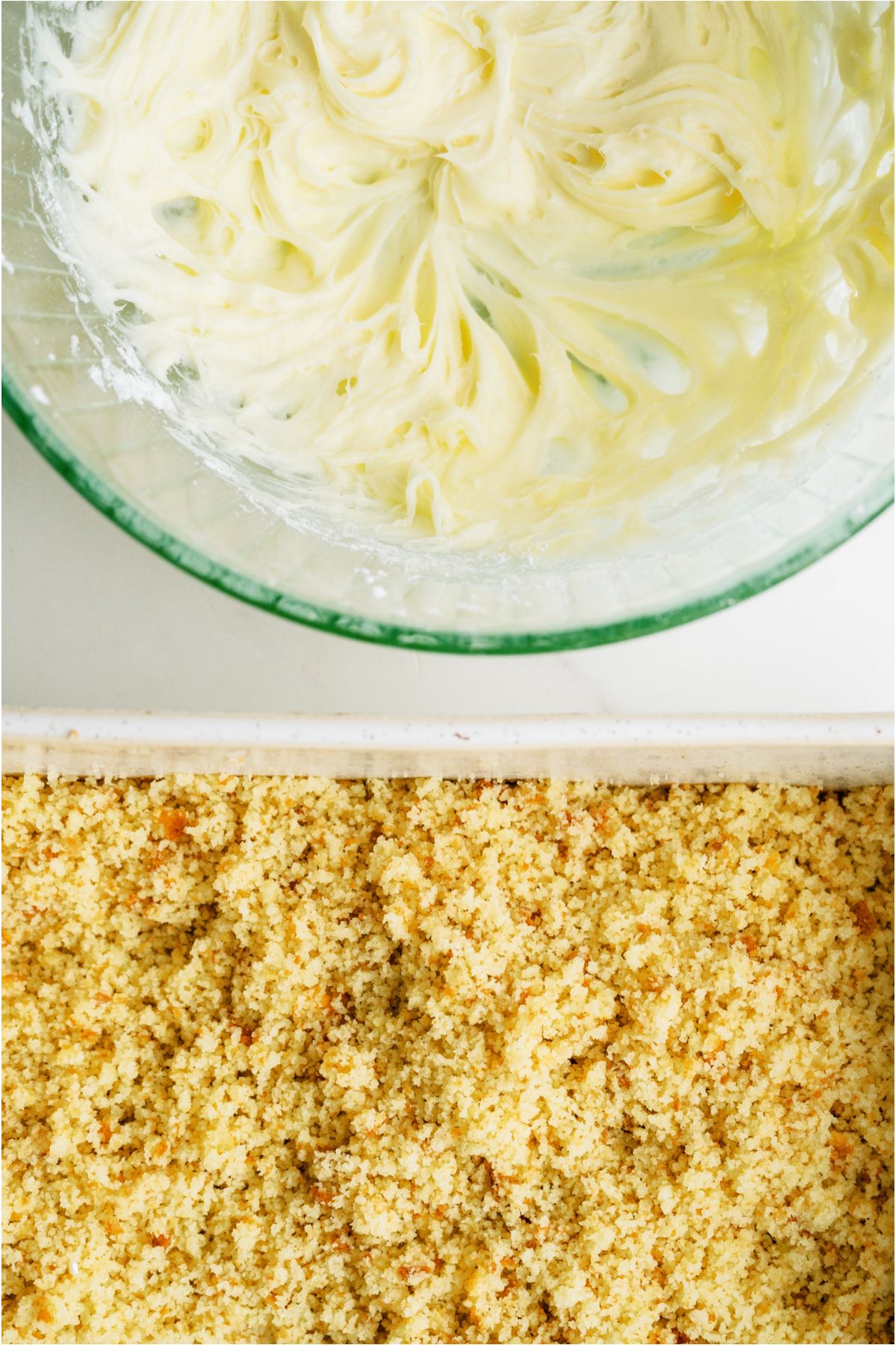 Frosting in a mixing bowl and a crumbled up cake in a cake pan.