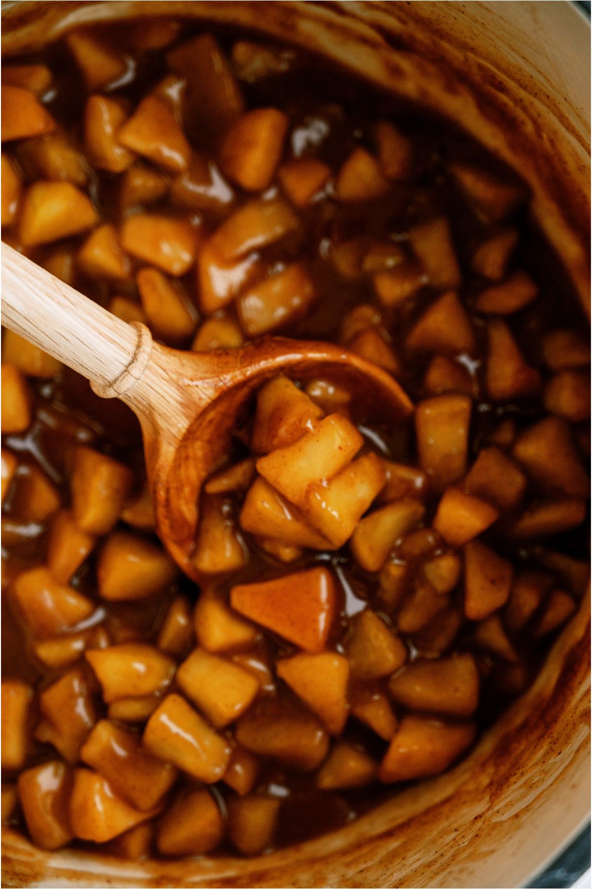 Close up of a wooden spoon in a saucepan of Apple Pie Filling.