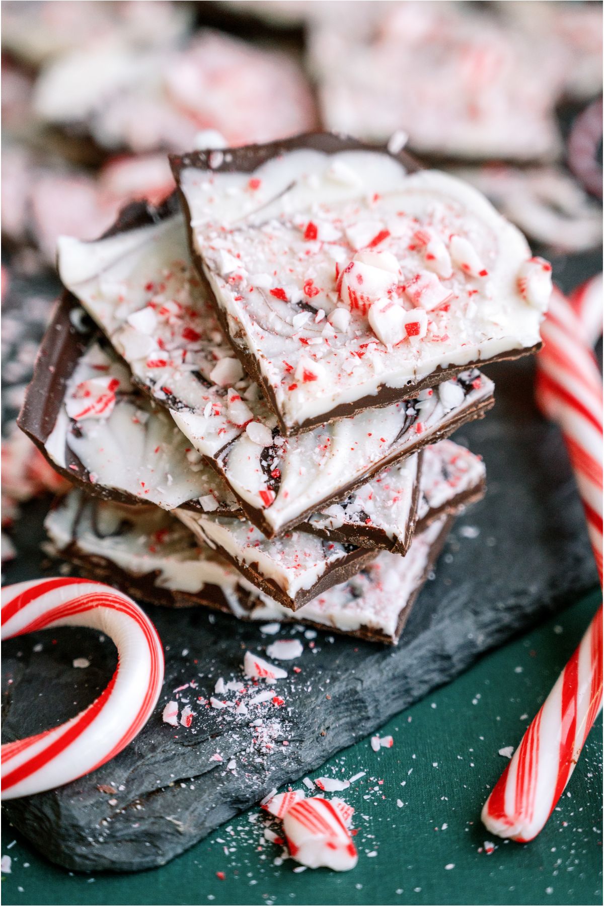 Top view of pieces of Peppermint Bark stacked surrounded by other pieces of Peppermint Bark and candy canes.
