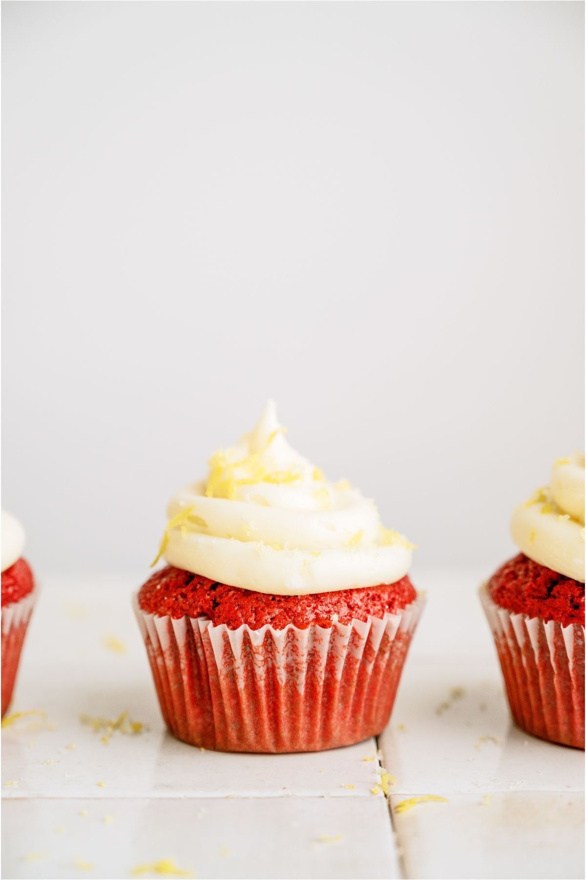 One Red Velvet Cupcake centered in the picture with cupcakes on both sides barely out of frame.