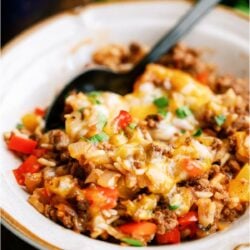 A white bowl with a serving of Stuffed Pepper Casserole in it with a spoon.