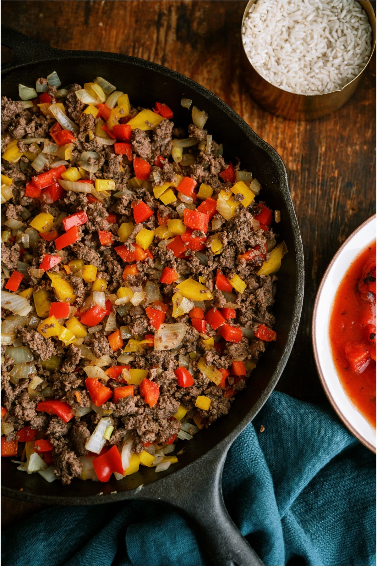 A skillet filled with cooked ground beef and diced onions and peppers.