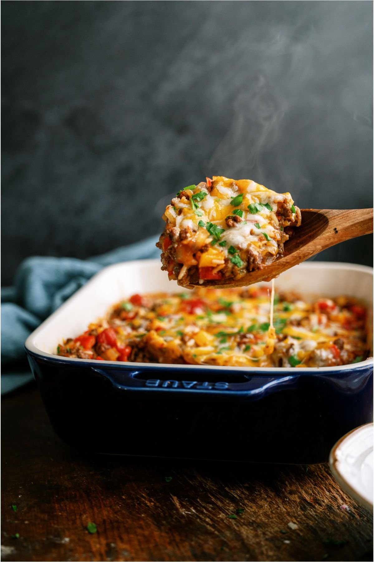 A wooden spoon lifting a scoop of Stuffed Pepper Casserole out.