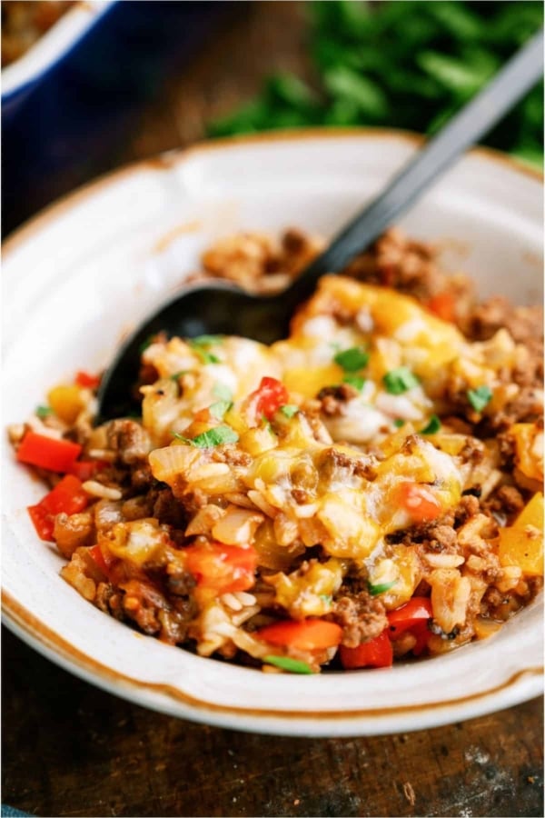 A white bowl with a serving of Stuffed Pepper Casserole in it with a spoon.