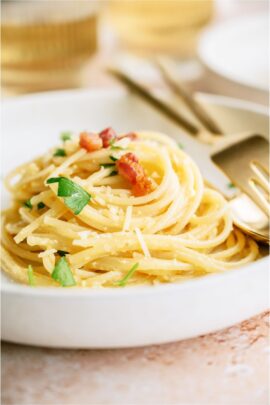 A white bowl of Classic Pasta Carbonara with af fork and spoon.