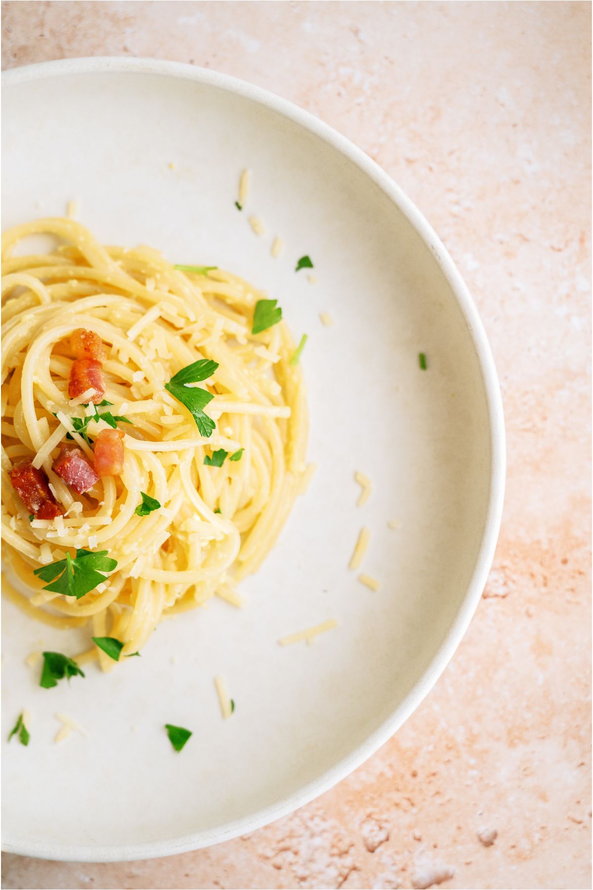 Top view of a plate with a servings of Classic Pasta Carbonara topped with diced tomatoes and fresh parsley.