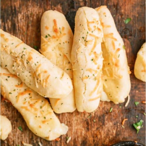 Copycat Bosco Sticks on a wooden background with a small bowl of marinara on the side.