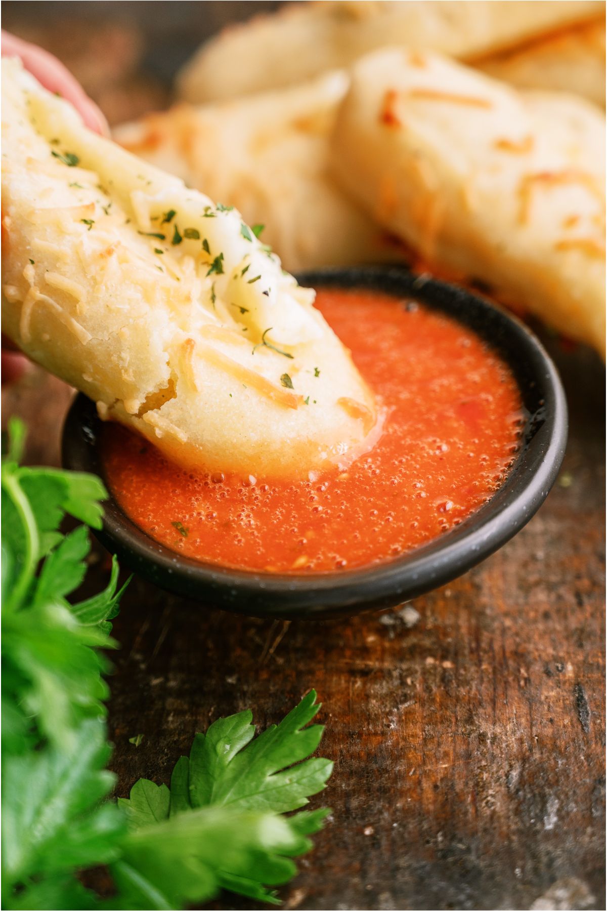 A Copycat Bosco Stick being dipped in a small bowl of marinara.