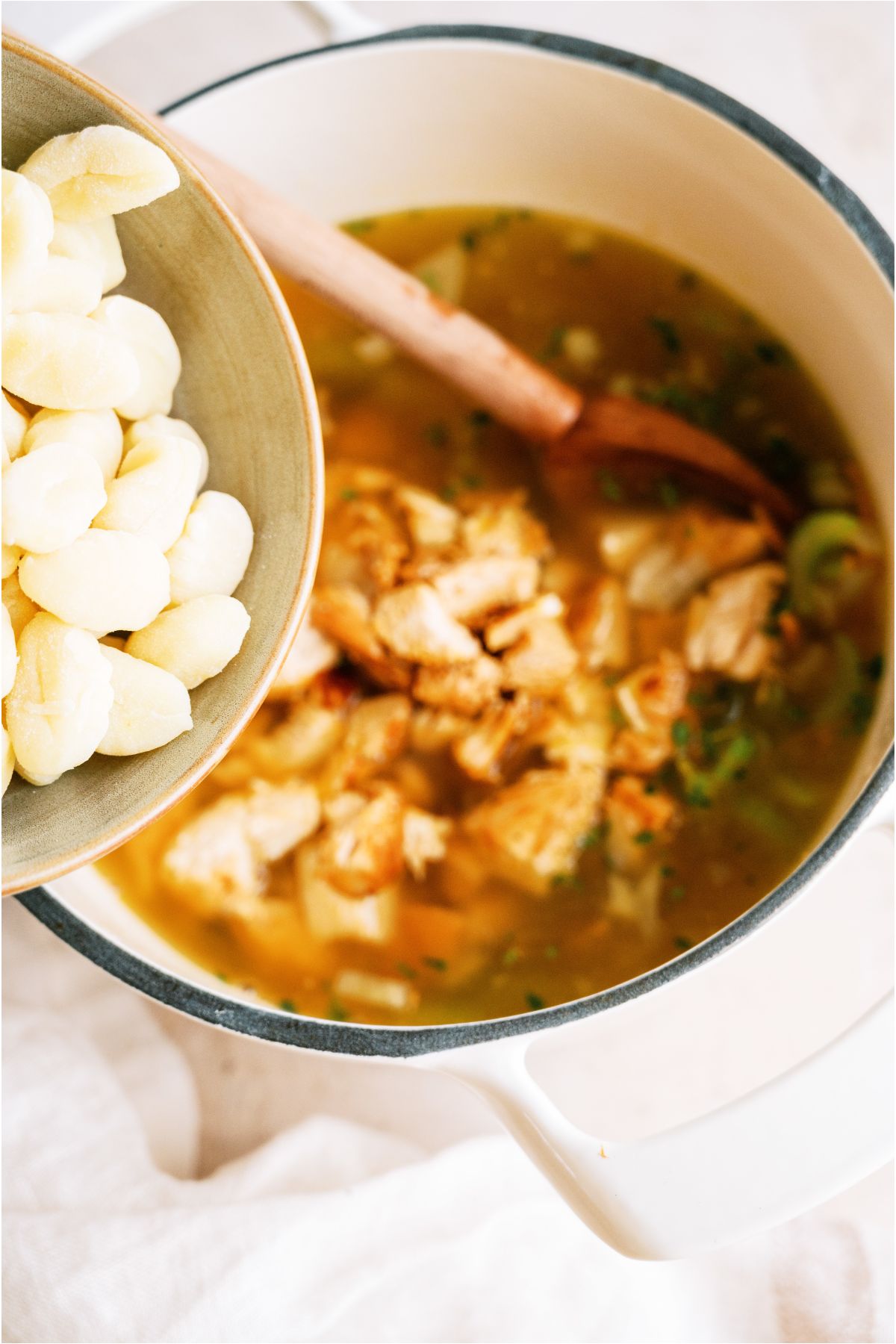 Adding potato gnocchi from a bowl into the stockpot.