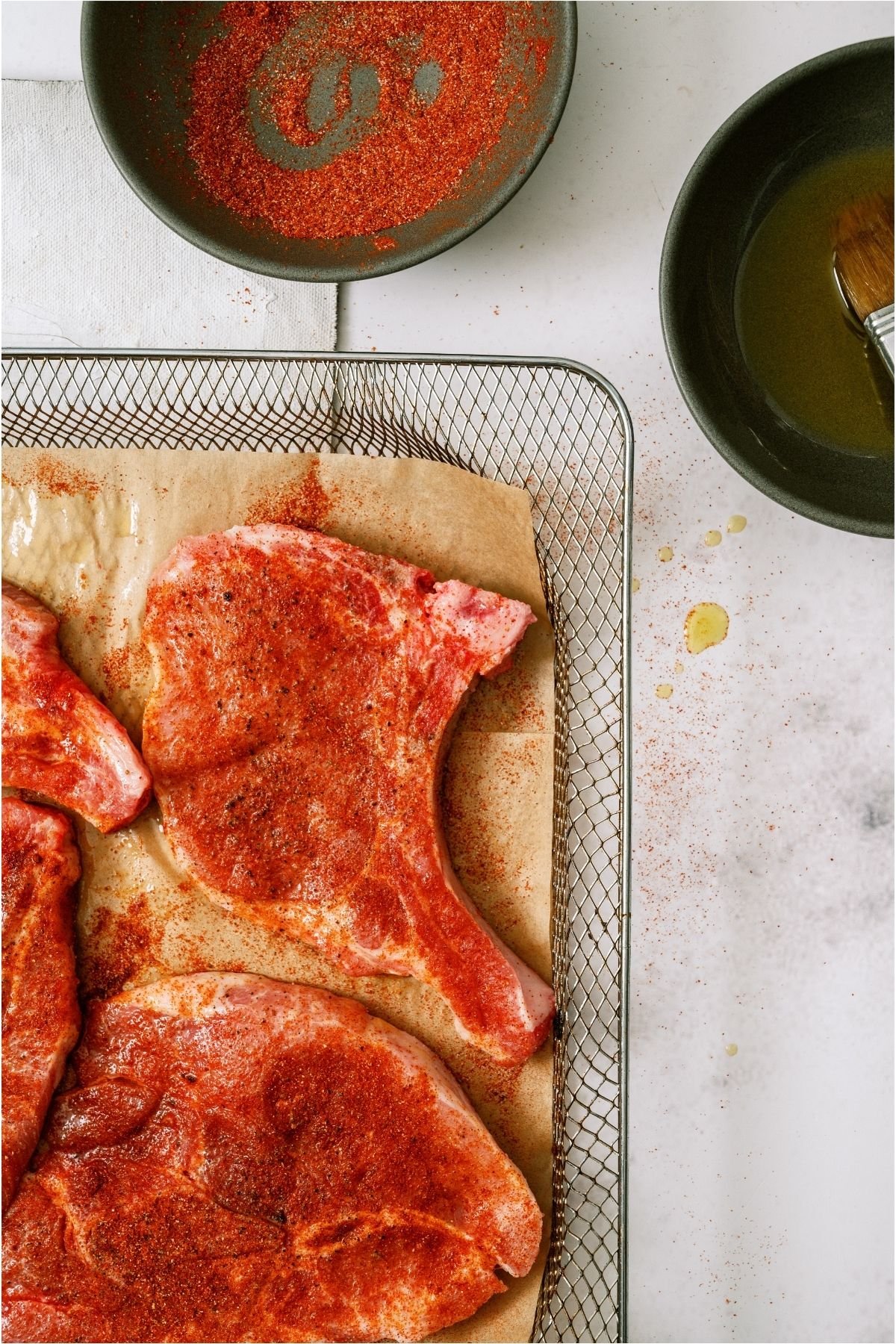Raw bone in pork chops with seasoning on them.