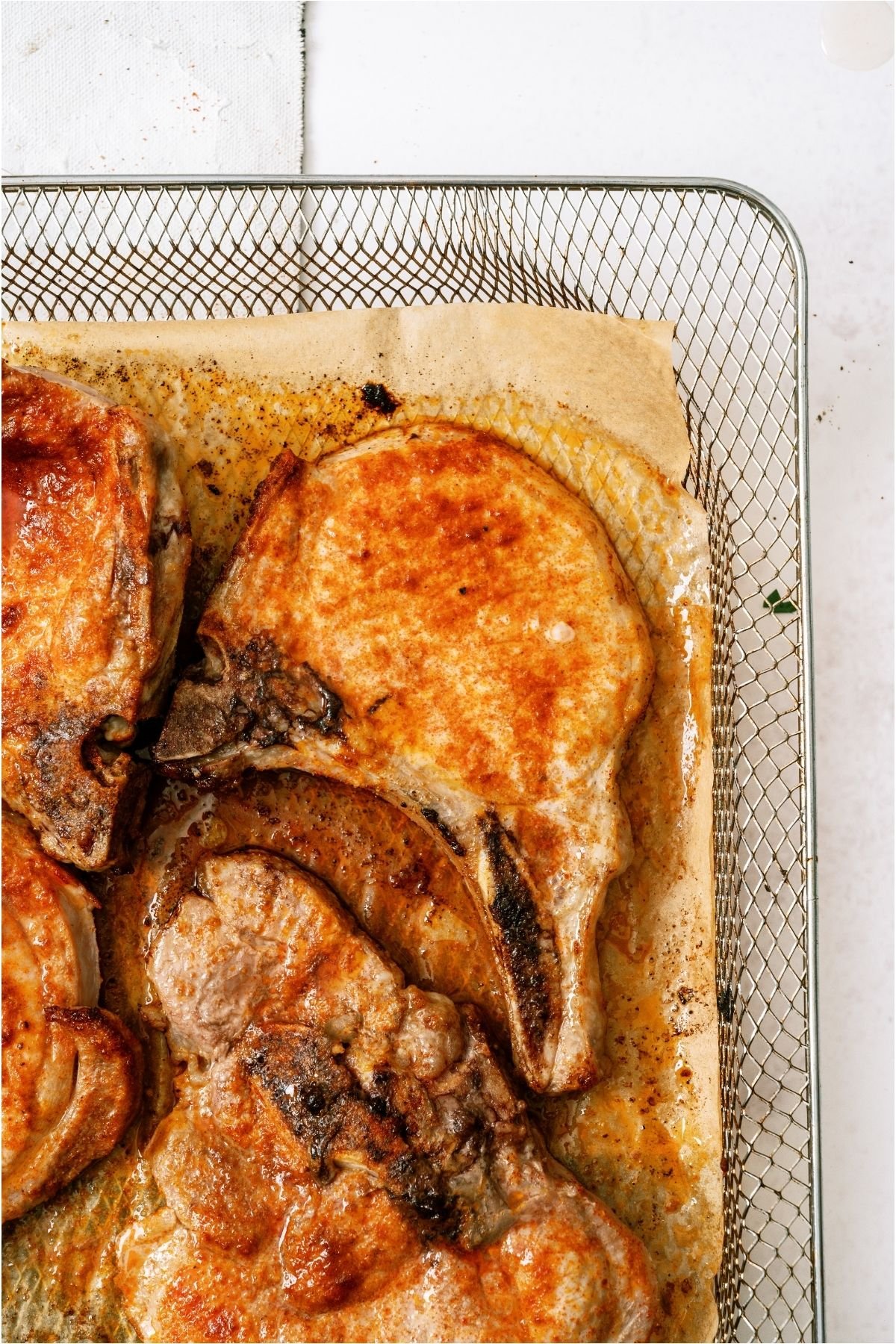 Air fryer pork chops cooked on top of parchment paper.