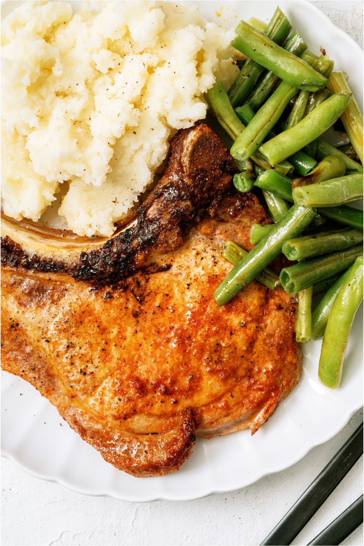 Air Fryer Pork Chop on a plate with green beans and mashed potatoes.