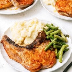 Air Fryer Pork Chops on plate with mashed potatoes and green beans.