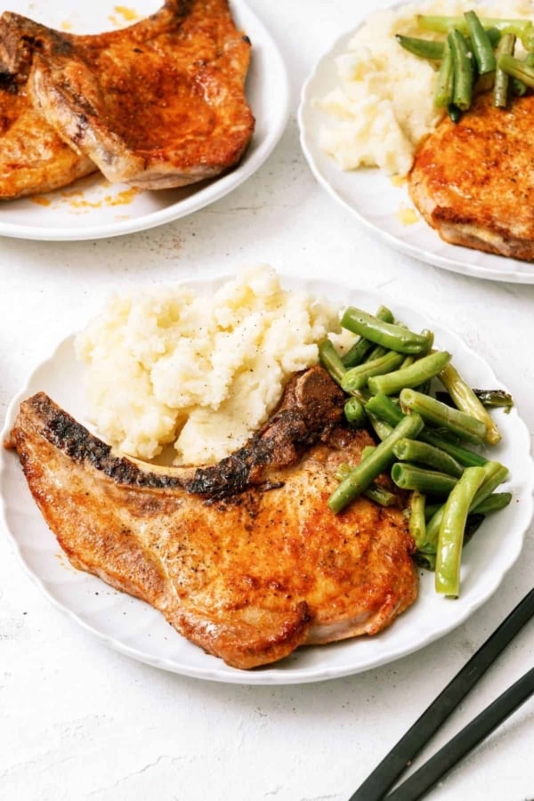 Air Fryer Pork Chops on plate with mashed potatoes and green beans.