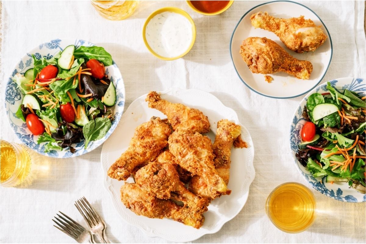 A plate of Crispy Fried Chicken with a smaller plate with 2 chicken pieces and 2 bowls of salad.