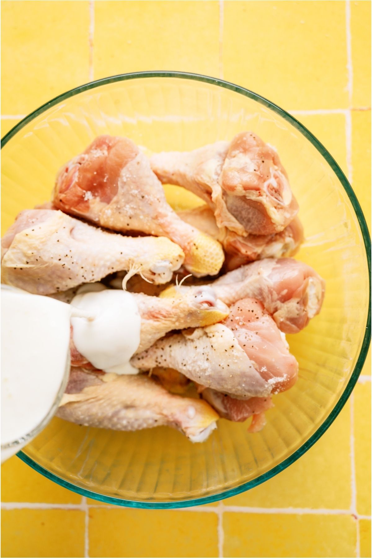 Buttermilk poured on chicken pieces in large mixing bowl.